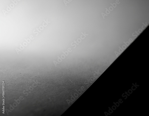 A minimalist abstract composition featuring a sharp diagonal division between bright white and deep black, with a subtle grey gradient.