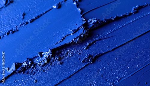 Rich textured abstract background featuring vibrant ultramarine blue pigment swatches with deep grooves and peaks created by a cosmetic or art application tool demonstrating intense color saturation