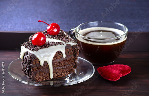 Celebratory chocolate cake with glaze and canned cherry, cup of coffee on the wooden tray.