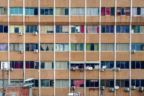 Tablou pe pânză Old apartment with colorful curtains in Jakarta, each window hinting at the harsh yet vibrant life of the city's crowded streets