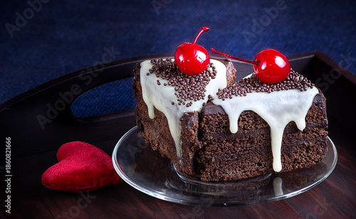Celebratory chocolate cake with glaze and canned cherry on the wooden tray.