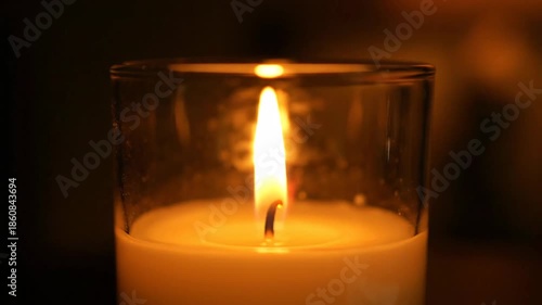 Warm flickering candle flame in glass creating a peaceful ambiance in the dark