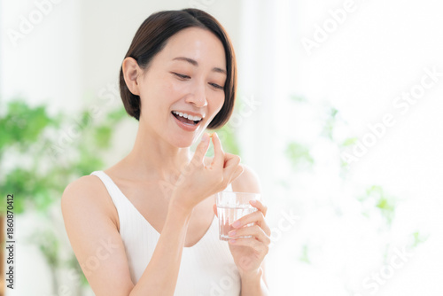 Photos リビングでサプリメントを飲むミドルの女性