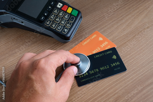 Healthcare cashless payment concept with a stethoscope placed on credit cards near an EDC terminal on a wooden desk. Perfect for healthcare, insurance, fintech, hospital, billing, and medical payment