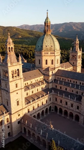 Majestic building with domed roof and towers, nestled against a forested mountain backdrop