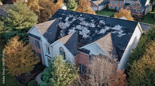 Roof with hail damage marked by inspection chalk concept. Aerial view of a house with damaged roof and fall foliage.