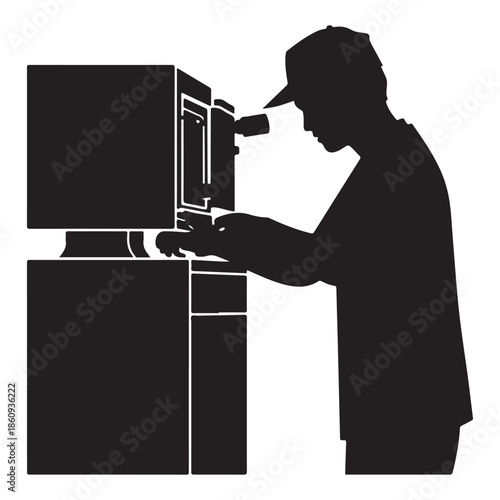  Man in cap silhouette intently engaging with an electronic device or computer system.