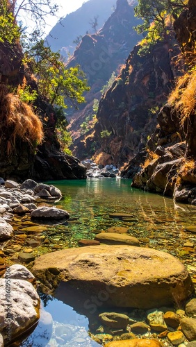 Wallpaper Mural A narrow valley frames a turquoise river reflecting sunlight, surrounded by rocky cliffs and golden vegetation. The sun shines brightly Torontodigital.ca
