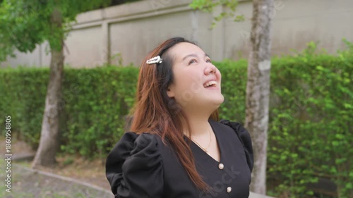Happy Asian woman walking and smiling in green park during daytime lifestyle portrait