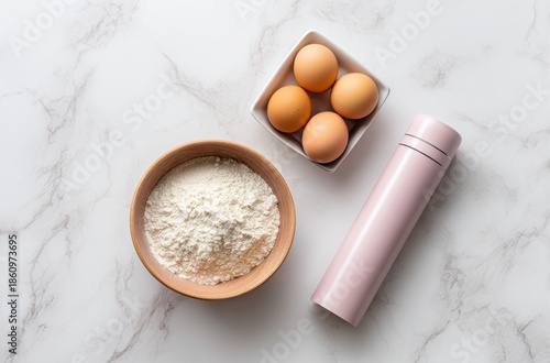 Fresh eggs, flour bowl, and pink portable foam maker on marble surface