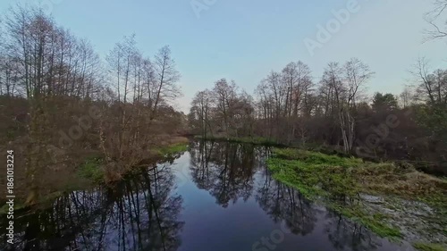 A low and fast drone flight over a river and meadow.
