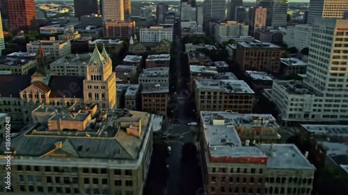 Aerial view of a city skyline at dusk, with buildings of various heights and architectural styles near a waterfront park