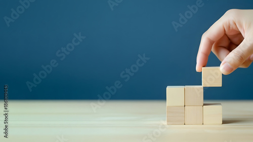 Hand placing a wooden block on top of stacked blocks