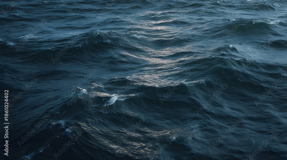 Fototapeta premium Dark textured ocean waves with subtle light glints across the dynamic surface of the deep blue sea