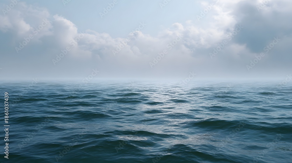 Fototapeta premium A serene hazy ocean expanse under a cloudy sky with gentle waves