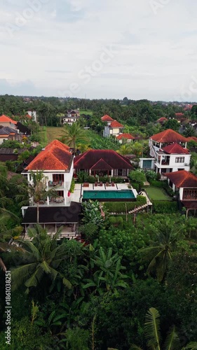 Wallpaper Mural Vertical video showing a tropical villa with swimming pool set at the edge of a green valley, surrounded by palm trees and open countryside, highlighting peaceful rural living. Torontodigital.ca
