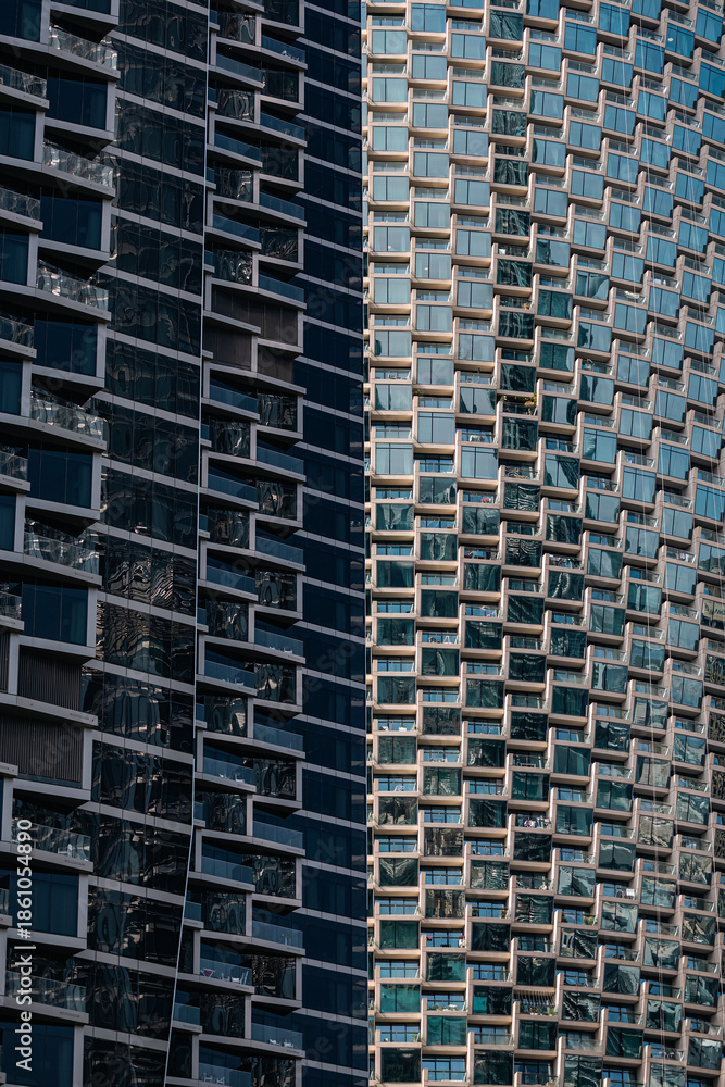Fototapeta premium two skyscrapers with geometric glass facade and strong shadow line. Urban architecture and abstract pattern for business or cityscape background.