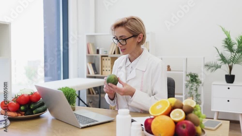 A dietitian consults with a client, holding an avocado while discussing nutrition and healthy eating habits in her office.