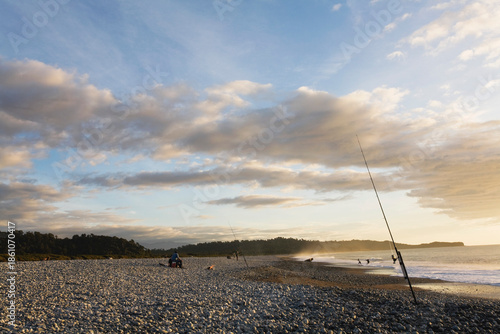 Fishing rods on Gillespies Beach Tasman Sea at sundown West Coast New Zealand
