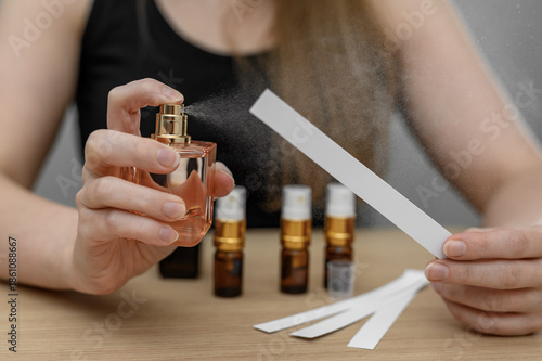 A woman tests the scent of perfume, smells fragrance compositions, sprays them on a blotter