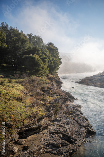 wallpaper of a river crossing a green rocky land with trees