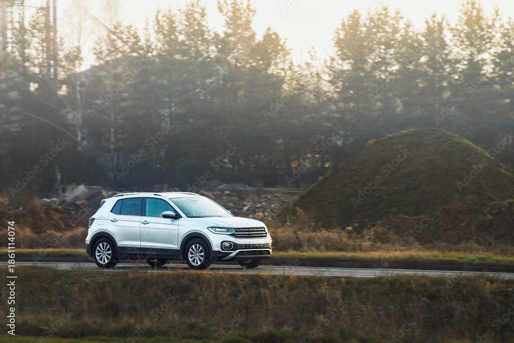 Fototapeta premium SUV on rural road with autumn trees