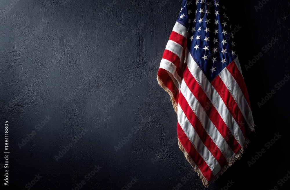 Obraz premium Worn and weathered national banner hangs against a dark background, with stars and stripes visible
