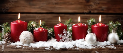 Festive red candles surrounded by holiday decorations on a snowy winter day