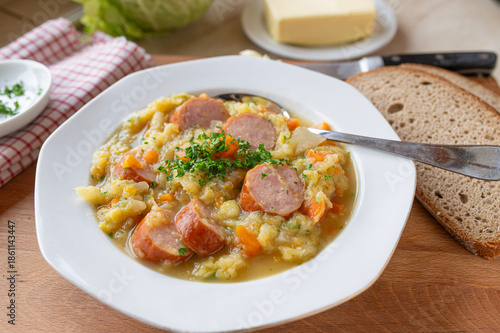 Obraz na płótnie Traditional german savoy potato stew with sausage on plate und rustic background