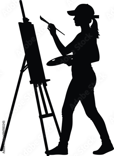 Silhouette of a female artist wearing a cap painting on a canvas with a brush and palette in a studio.