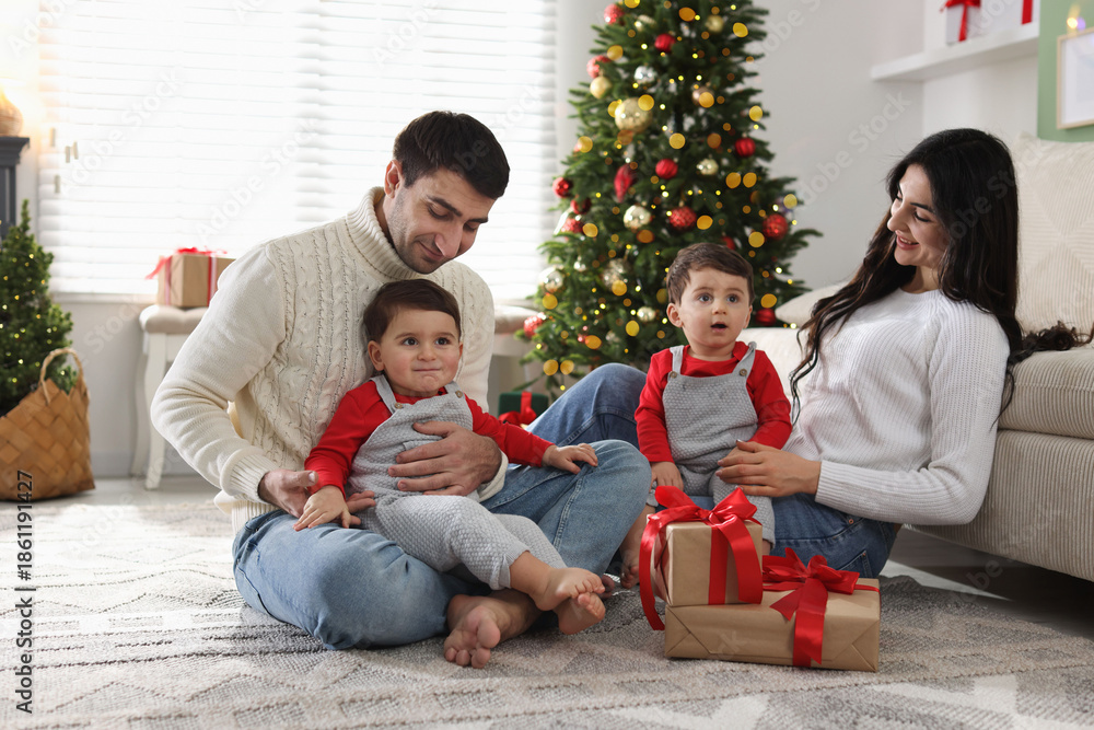 Fototapeta premium Parents and their cute twin babies with Christmas gifts at home