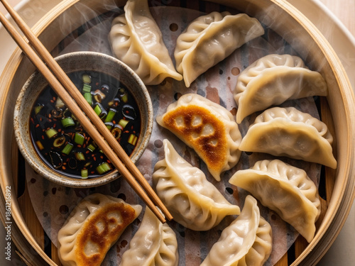 Steamed dumplings served in bamboo basket with dipping sauce, traditional Asian food concept, fresh homemade cuisine and comfort meal, ideal for restaurant menus, food blogs, delivery services