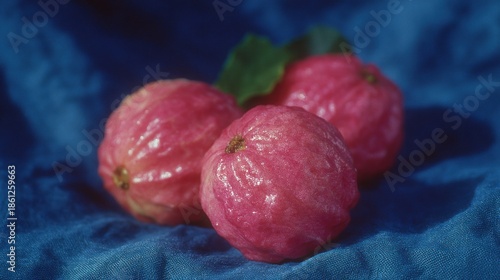 Vibrant pink guavas resting on a blue fabric backdrop in soft natural light