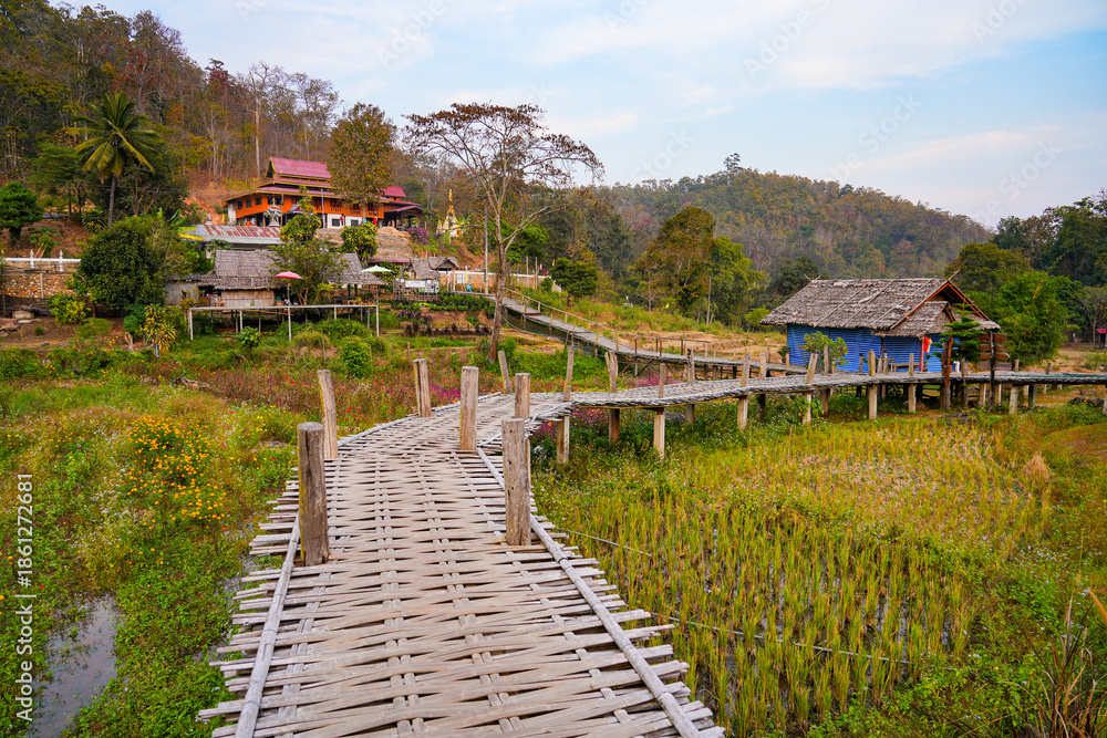 Fototapeta premium The winding Kho Ku So Bamboo Bridge stretching across dry rice paddies in Pai, Northern Thailand