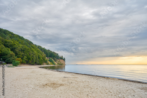 A quiet sandy beach in Gdynia Orłowo stretches along the calm waters of the Baltic Sea.    