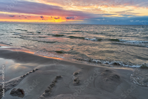 Beautiful landscape of sunset by baltic sea. Golden, shining sun going down and cloudy, colorful sky.	