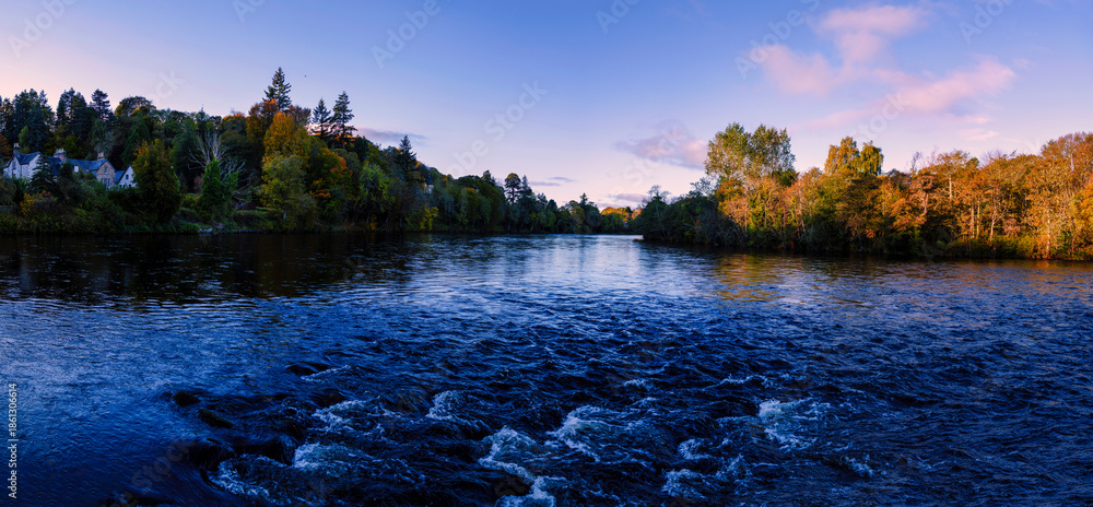 Fototapeta premium Ness Island at Sunrise in the River Ness in Inverness, Scotland, with tranquil autumn foliage, quiet forest, and gentle water flow