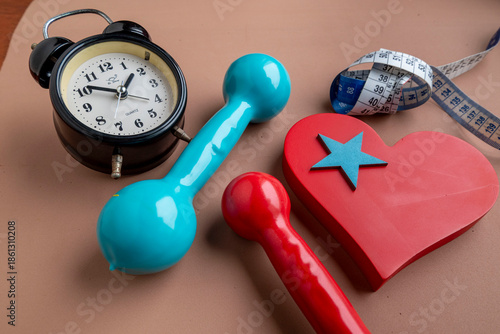 Heart-shaped, with weights for exercise and a measuring tape. Hourto start exercising.