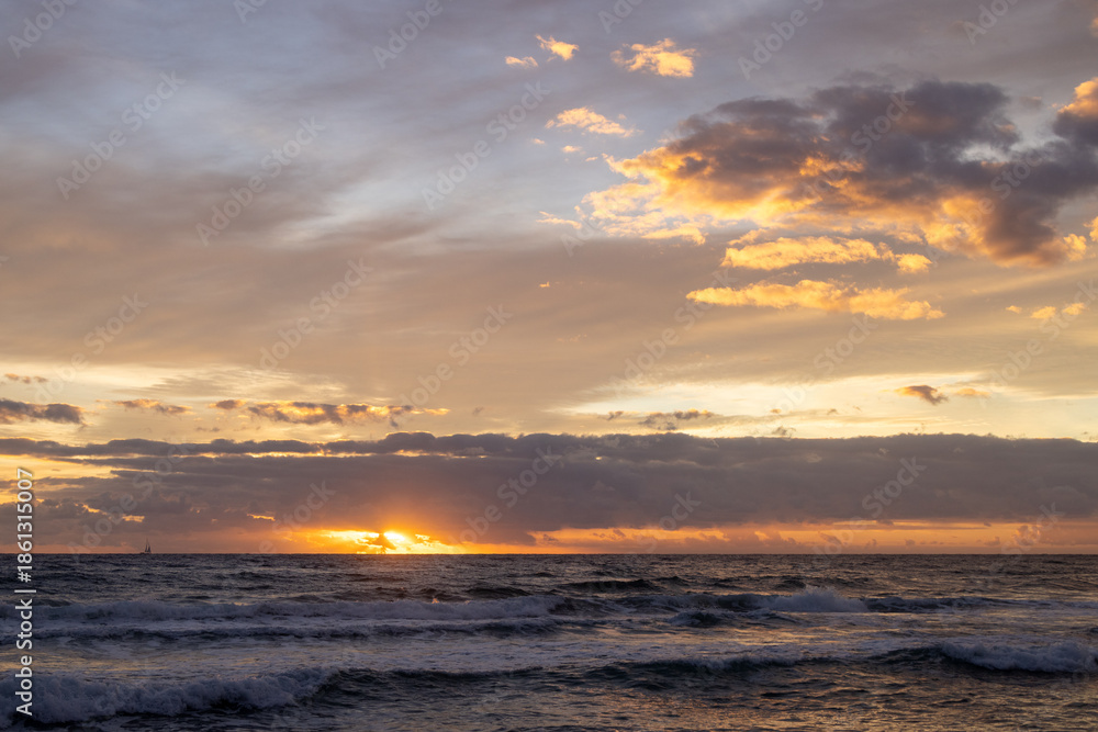 Obraz premium Golden Sunrise Breaking Through Clouds Over Ocean