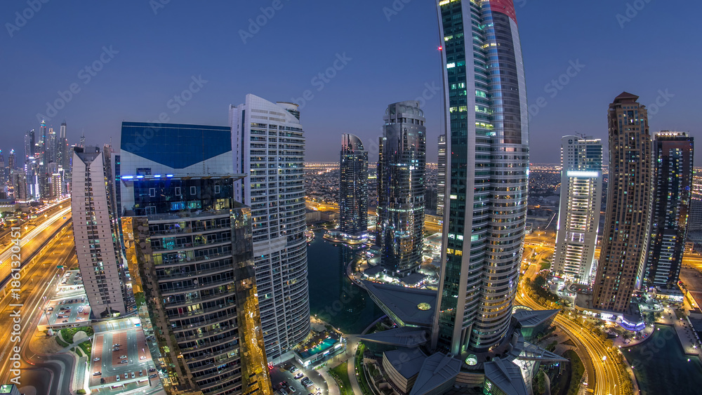 Obraz premium Buildings of Jumeirah Lakes Towers after sunset with traffic on the road day to night timelapse.