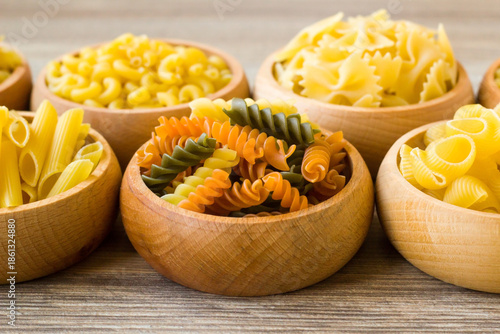 Turkish spiral pasta with tomatoes and spinach was designed in bamboo bowl on wooden surface with various pasta