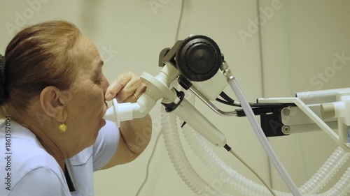 Elderly woman undergoing a spirometry test at a hospital clinic, exhaling into a device to assess lung capacity and identify respiratory issues such as asthma or copd