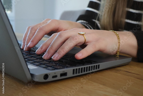 Woman typing on a laptop keyboard while working at desk, modern office workflow and digital work concept