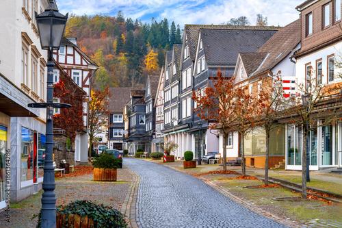 Bad Laasphe, Siegen-Wittgenstein, historic old town street with timber houses, paved road, shop windows and autumn trees in background