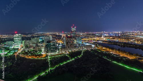 Aerial panoramic view over Vienna city with skyscrapers, historic buildings and a riverside promenade day to night timelapse in Austria.