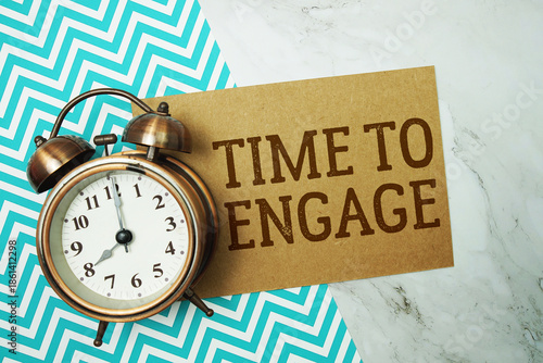 Foto Time To Engage text written on paper card with alarm clock on marble background