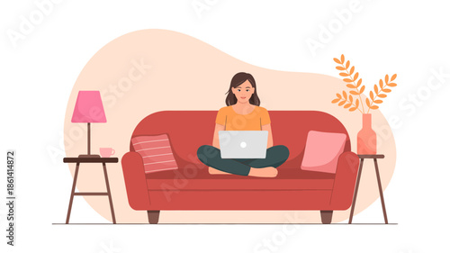 Woman comfortably working from home on her laptop, sitting cross-legged on a red couch