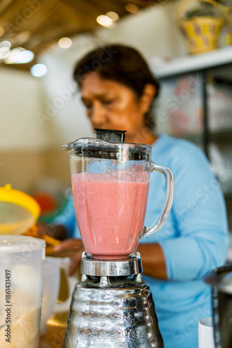 Woman preparing fruit smoothie in rustic cafe