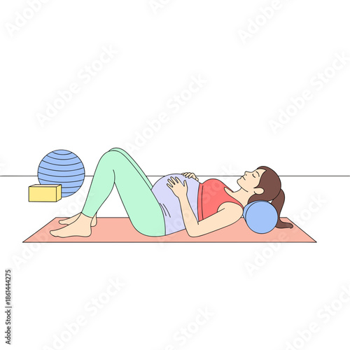 Pregnant woman relaxing on mat with exercise props in studio  