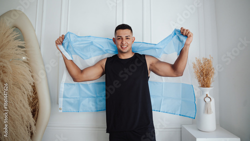 Quadro su tela Smiling young athlete holding the Argentine flag, celebrating victory and sporti